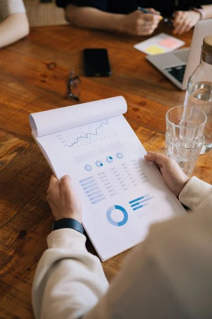 Hands at work on a laptop with cryptocurrency charts and a smartphone screen visible, centered on digital finance.